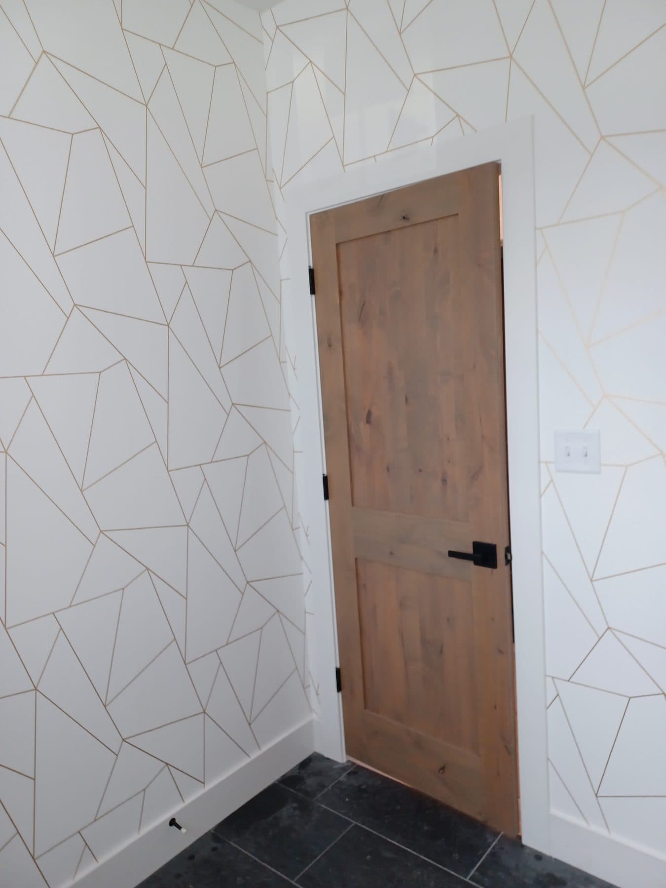 Bathroom with geometric wallpaper, wood door and black-trimmed window