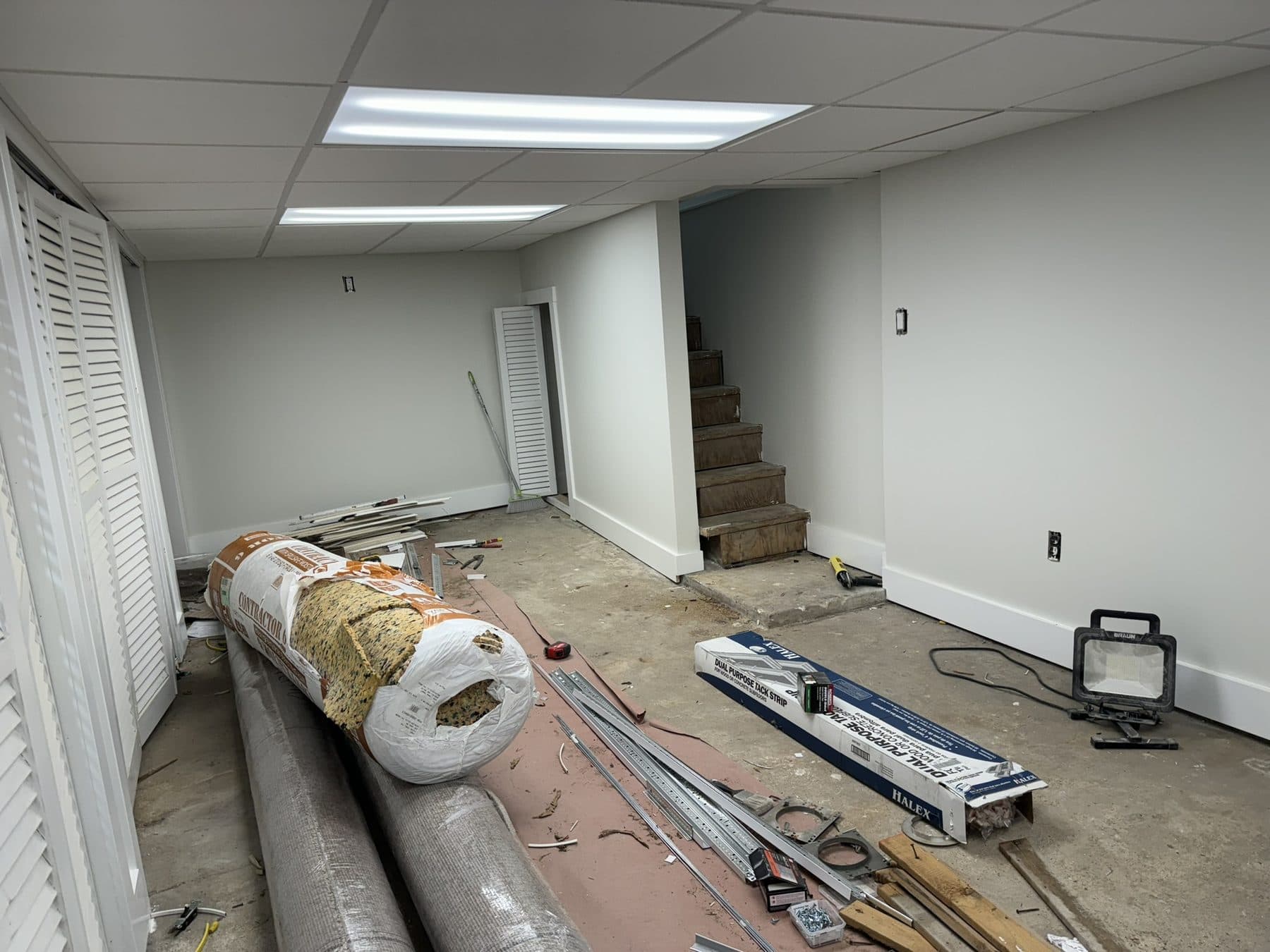 Basement during carpet installation, rolls still on the floor