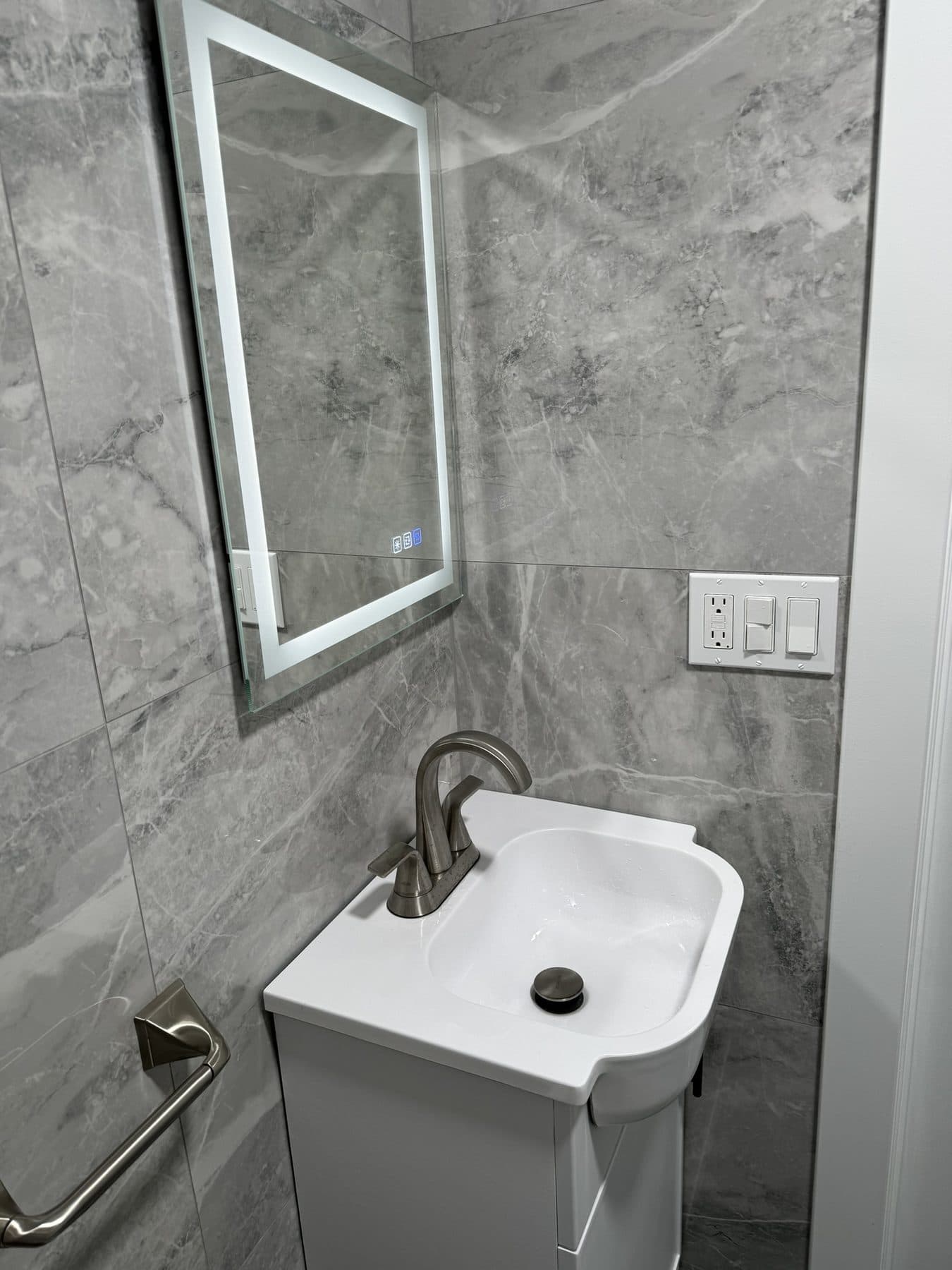 Compact bathroom with glass shower, wall sink and grey tile