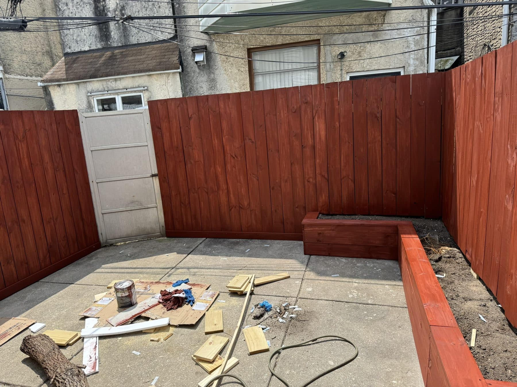 Cedar privacy fence being built and stained in a rowhome yard